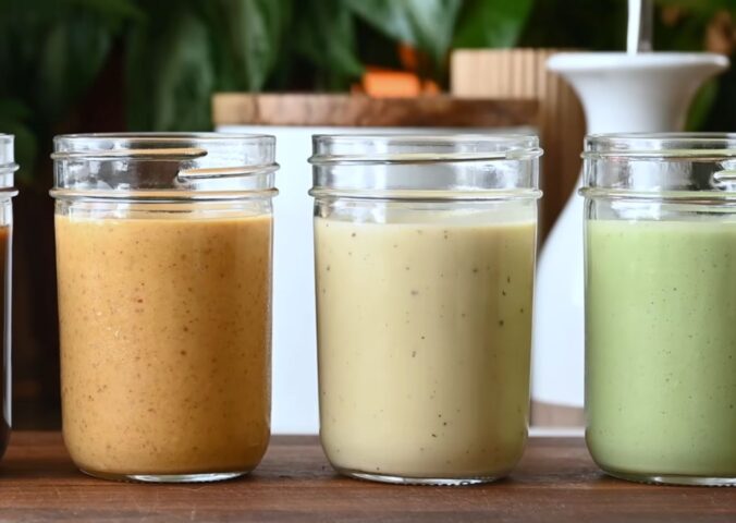 Several jars of Nisha Vora's homemade salad dressings lined up on a cutting board.
