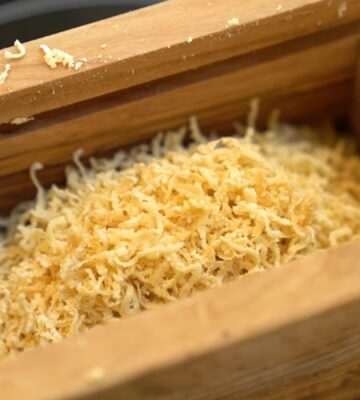 Schinner's vegan parmesan in a wooden grating box with the lid removed