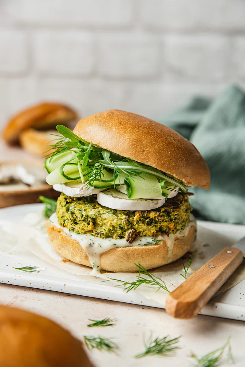 Spring Burger with courgette and pea cakes, a soy yogurt sauce, and goats cheese alternative