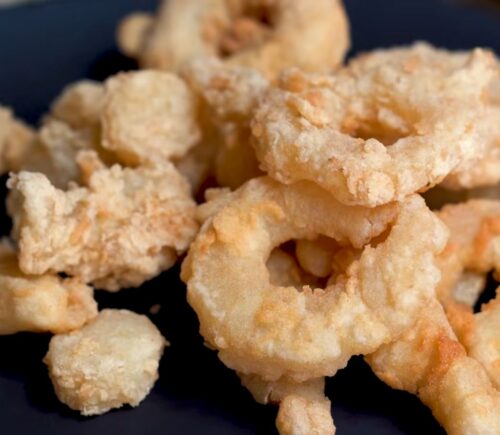 A plate of golden fried calamari rings made from konjac, using Miyoko Schinner's vegan calamari recipe.