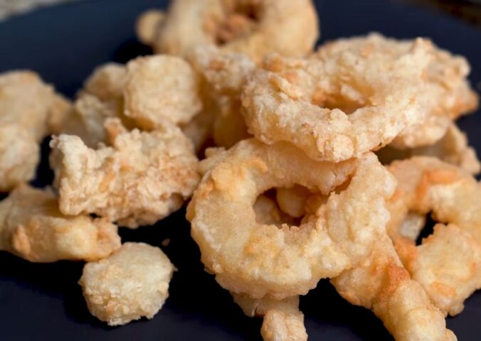 A plate of golden fried calamari rings made from konjac, using Miyoko Schinner's vegan calamari recipe.