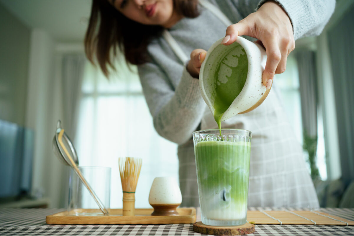 Photo shows a woman pouring a matcha latte from a jug into a glass. Alpro just launched the UK’s first matcha-flavored coconut and soy milk