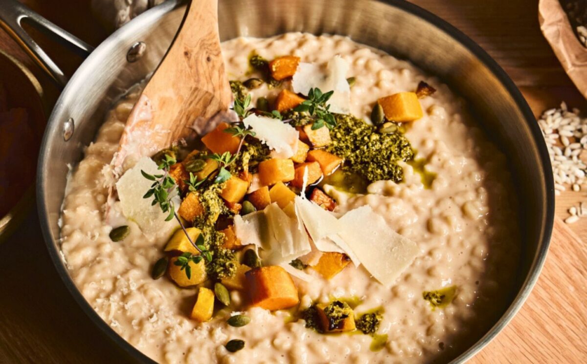 a pan of butternut squash risotto with cognac, pumpkin seed pesto, and fried thyme blossom for vegan risotto recipes