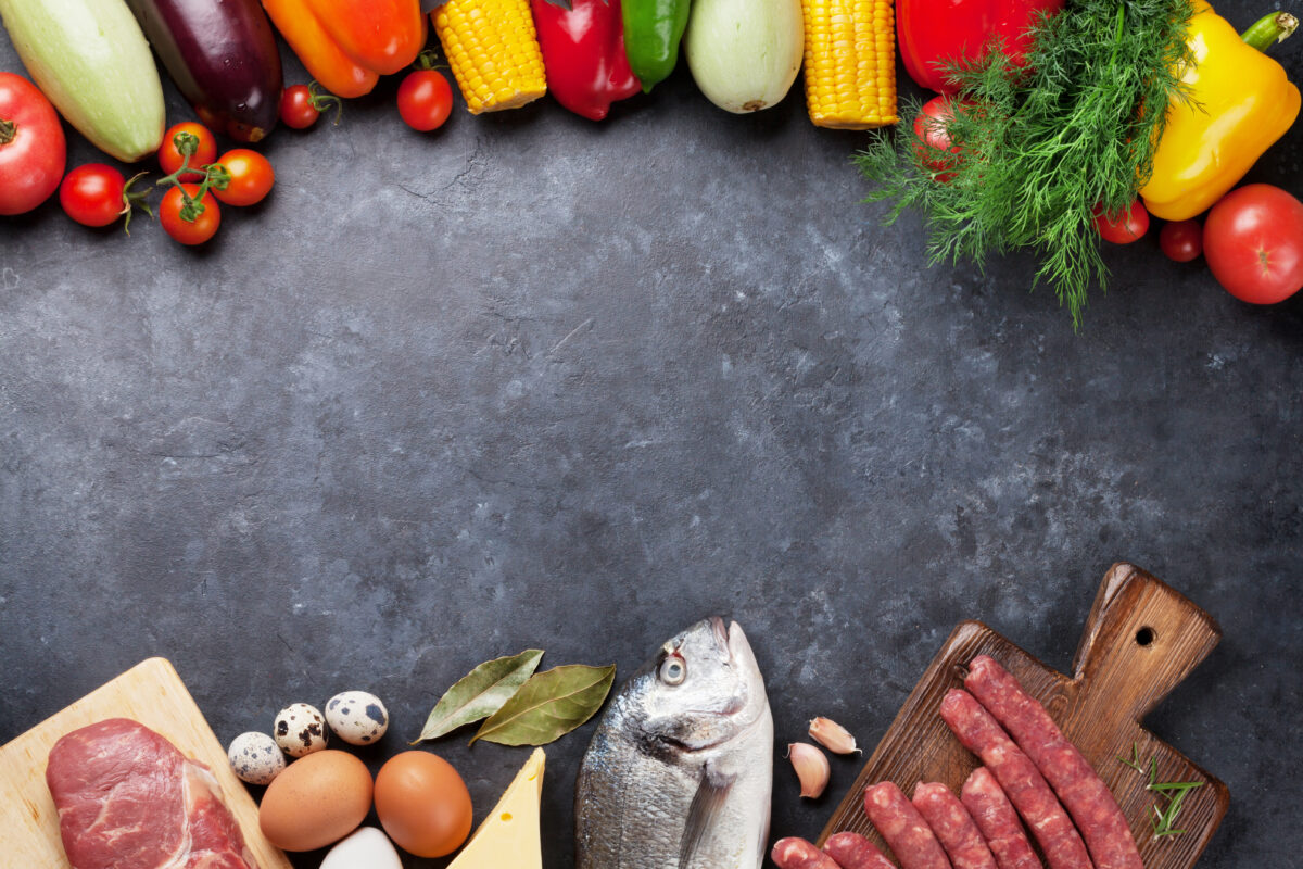 Photo shows a row of fresh vegetables, fruits, and other plant foods along the top, and a row of red meat, eggs, fish, and sausages along the bottom
