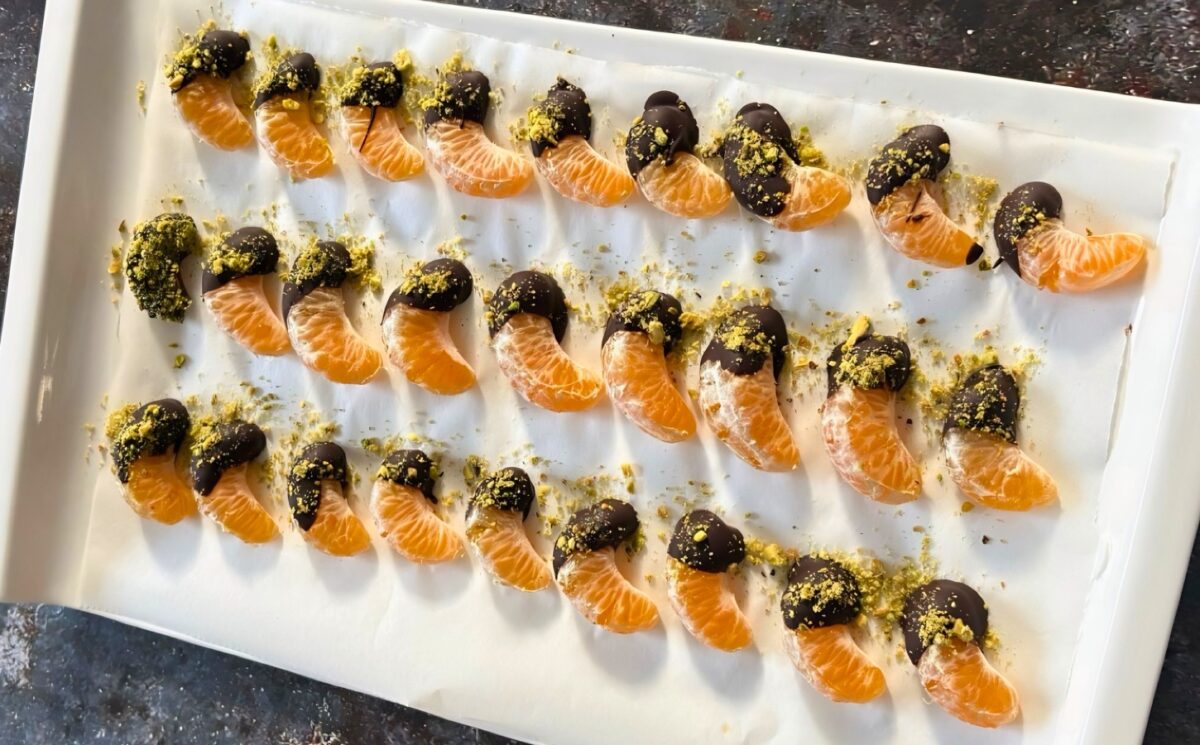 vegan chocolate mandarins with one half covered in chocolate and pistachio for vegan citrus recipes