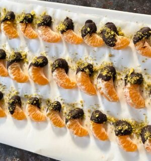 vegan chocolate mandarins with one half covered in chocolate and pistachio for vegan citrus recipes