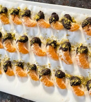 vegan chocolate mandarins with one half covered in chocolate and pistachio for vegan citrus recipes