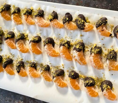 vegan chocolate mandarins with one half covered in chocolate and pistachio for vegan citrus recipes