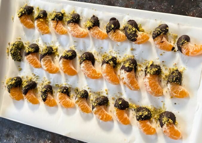 vegan chocolate mandarins with one half covered in chocolate and pistachio for vegan citrus recipes