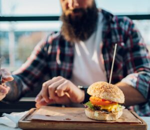 Photo shows a man with a beard about to eat a burger. Two new studies show that swapping processed meat for plant-based alternatives can significantly increase fiber intake and reduce salt and saturated fat consumption.