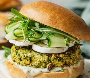 Spring Burger with courgette and pea cakes, a soy yogurt sauce, and goats cheese alternative