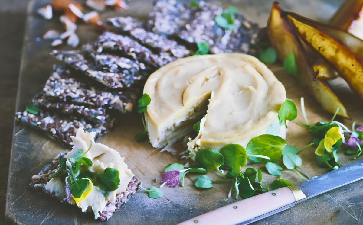 a board of truffled cashew cheese and caramelized pears with seed crackers for vegan charcuterie