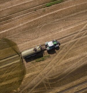Photo shows a tractor and trailer spreading manure on a field. A new “Ammonia Map” shows that the UK’s pollution hotspots correlate with factory farms