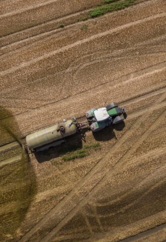 Photo shows a tractor and trailer spreading manure on a field. A new “Ammonia Map” shows that the UK’s pollution hotspots correlate with factory farms