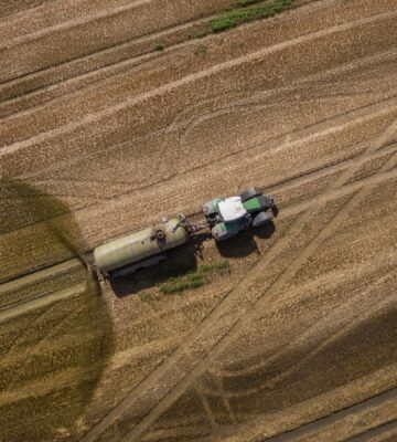 Photo shows a tractor and trailer spreading manure on a field. A new “Ammonia Map” shows that the UK’s pollution hotspots correlate with factory farms