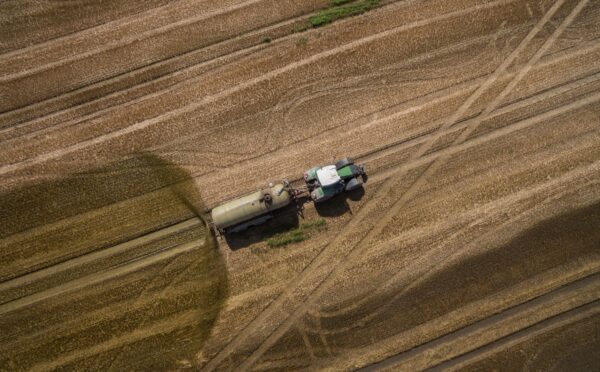 Photo shows a tractor and trailer spreading manure on a field. A new “Ammonia Map” shows that the UK’s pollution hotspots correlate with factory farms