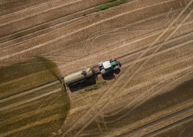 Photo shows a tractor and trailer spreading manure on a field. A new “Ammonia Map” shows that the UK’s pollution hotspots correlate with factory farms