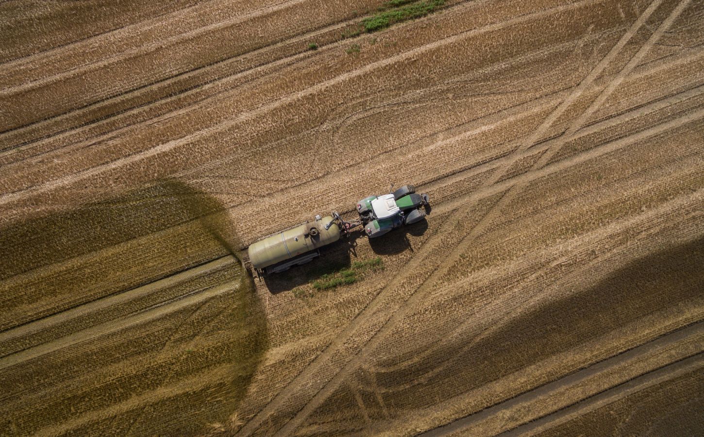 Photo shows a tractor and trailer spreading manure on a field. A new “Ammonia Map” shows that the UK’s pollution hotspots correlate with factory farms