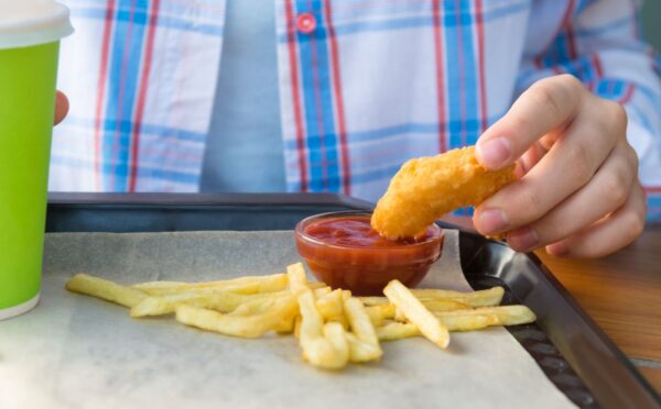 Photo shows a child dipping a chicken nugget into tomato ketchup on a tray with some french fries. The UK government is expected to announce a ban on fried foods such as chicken nuggets, battered fish and chips, and jam doughnuts in school dinners
