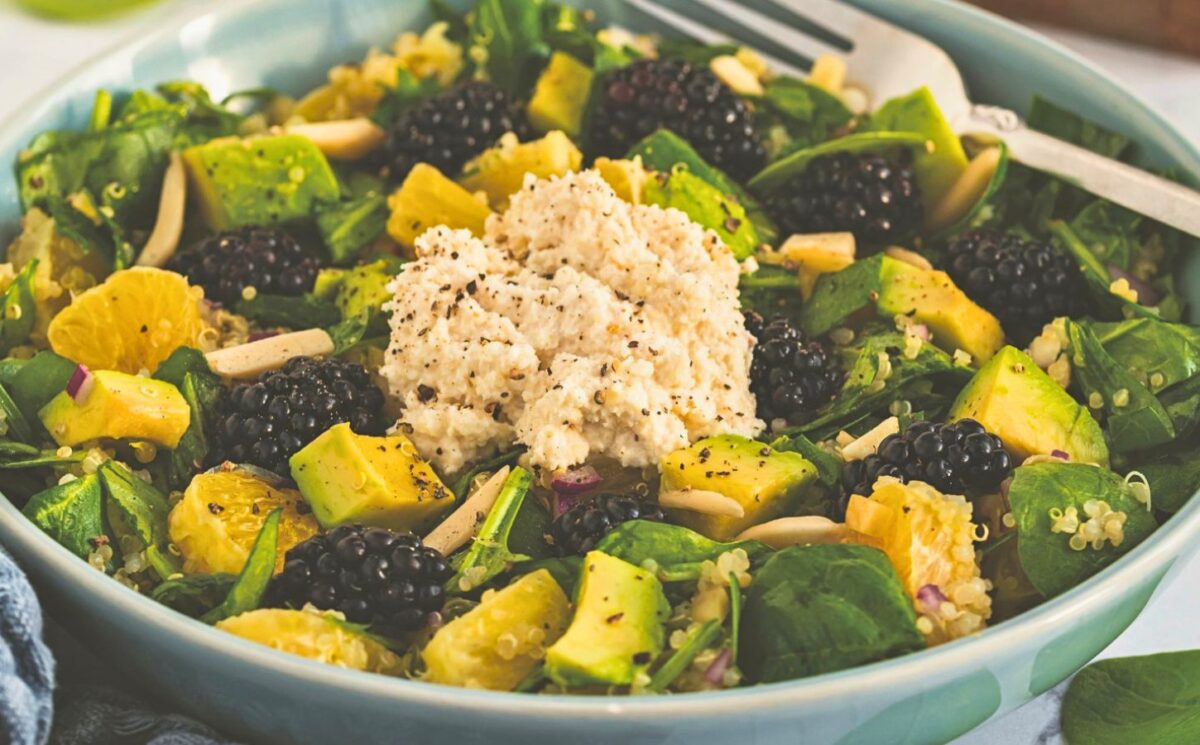 a bowl of bright and lively citrus salad made with quinoa, spinach, macadamia nut ricotta, and blackberries for vegan citrus recipes