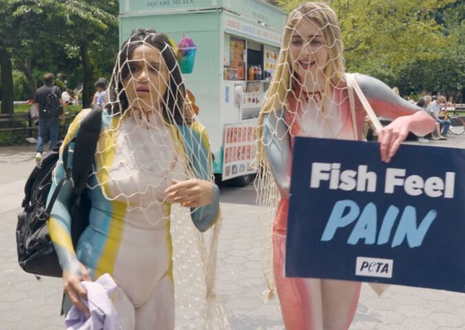 Photo shows a scene from the pilot episode of Green Goddesses Take New York, a reality comedy show from UnchainedTV that follows follows real life friends Justina Adorno and Jamie Logan as they get body-painted as endangered fish and do yoga in Times Square