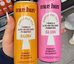 Photo shows a hand holding two flavors of the new fizzy drink, Mushus. Met Foods just launched Mushus, a range of sparkling, functional fruit drinks that target beauty and gut health