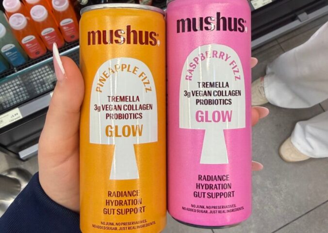 Photo shows a hand holding two flavors of the new fizzy drink, Mushus. Met Foods just launched Mushus, a range of sparkling, functional fruit drinks that target beauty and gut health