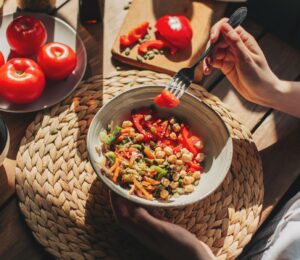 Photo shows someone eating a bowl of colorful plant-based foods at a sunny table. Adfree Cities says it is “proud” of backing the Ten Point Plan for Plant-Rich Diets.
