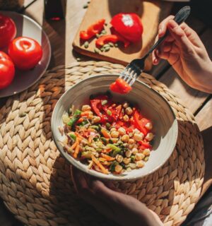 Photo shows someone eating a bowl of colorful plant-based foods at a sunny table. Adfree Cities says it is “proud” of backing the Ten Point Plan for Plant-Rich Diets.
