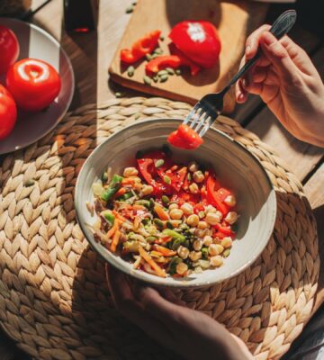 Photo shows someone eating a bowl of colorful plant-based foods at a sunny table. Adfree Cities says it is “proud” of backing the Ten Point Plan for Plant-Rich Diets.