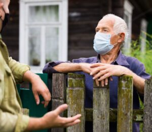 Photo shows two men in face masks talking over a wooden fence. Is factory farming already a public health crisis?