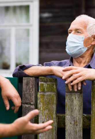 Photo shows two men in face masks talking over a wooden fence. Is factory farming already a public health crisis?