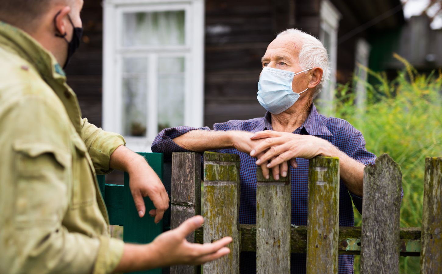 Photo shows two men in face masks talking over a wooden fence. Is factory farming already a public health crisis?