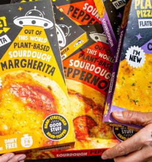 Photo shows Joe Hill, the co-founder of One Planet Pizza, holding a selection of the brand's frozen vegan pizzas and cheesy garlic bread. One Planet Pizza has passed £1 million in annualised retail sales for the first time ever