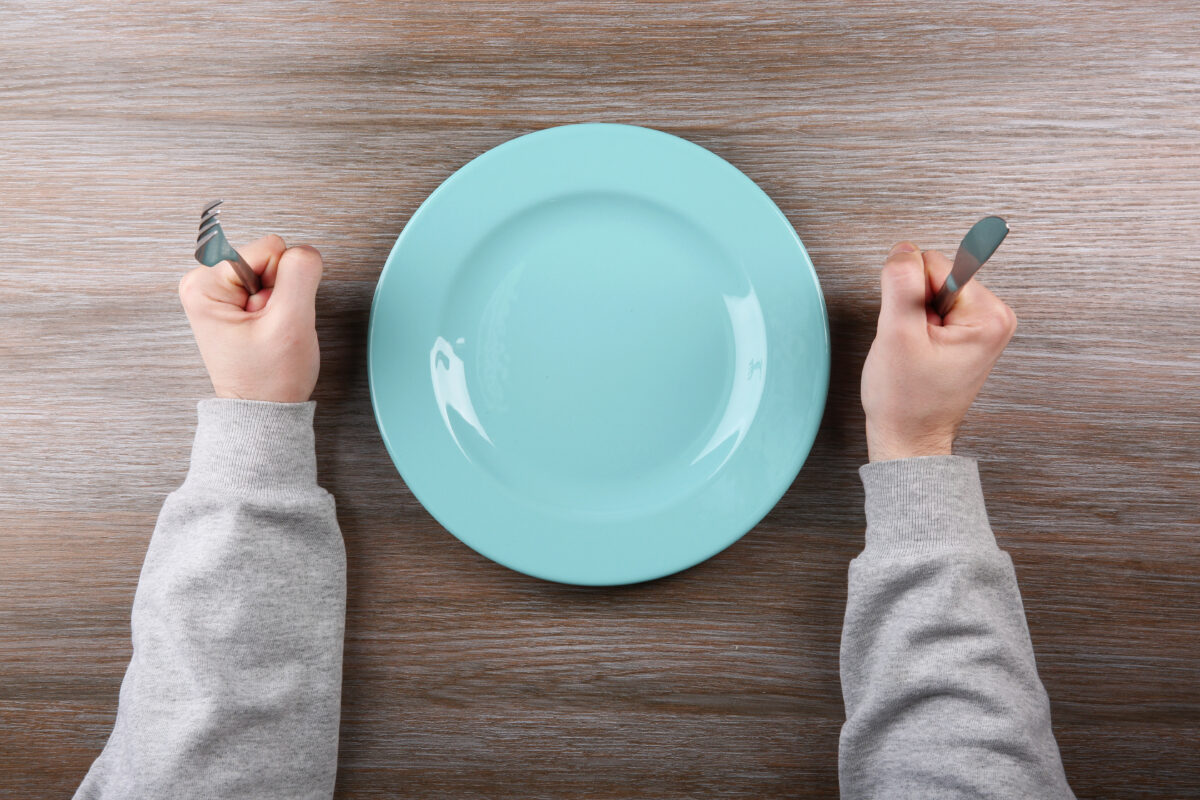 Photo shows a man's hands holding a knife and fork either side of an empty plate. A new study has found that people are more likely to say that they’re vegan than to actually follow a vegan diet