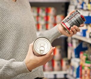 Photo shows a women holding up two cans of food in the supermarket and reading the packaging. A new study has found that people are more likely to say that they’re vegan than to actually follow a vegan diet