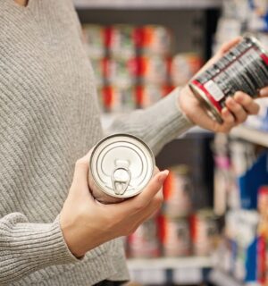 Photo shows a women holding up two cans of food in the supermarket and reading the packaging. A new study has found that people are more likely to say that they’re vegan than to actually follow a vegan diet