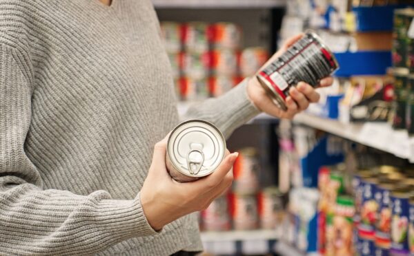 Photo shows a women holding up two cans of food in the supermarket and reading the packaging. A new study has found that people are more likely to say that they’re vegan than to actually follow a vegan diet