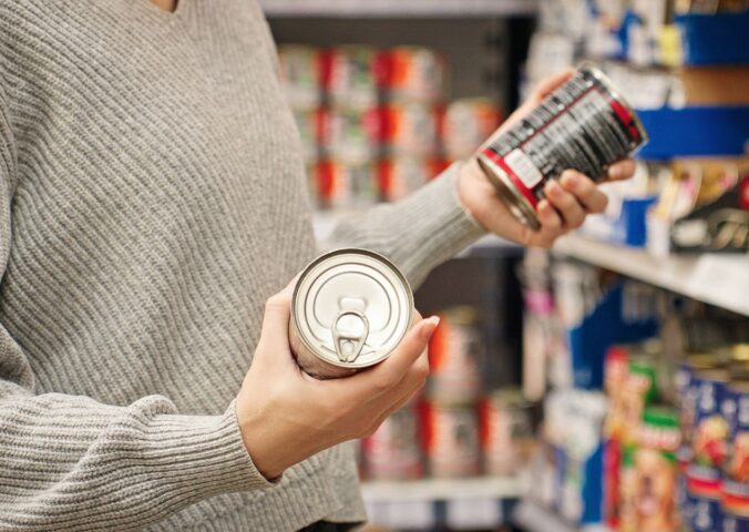 Photo shows a women holding up two cans of food in the supermarket and reading the packaging. A new study has found that people are more likely to say that they’re vegan than to actually follow a vegan diet