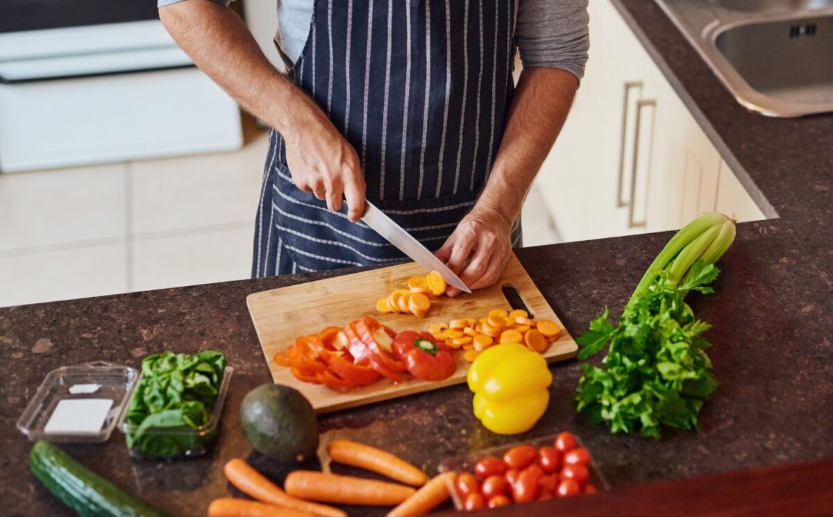 Photo shows a man cutting vegetables in a kitchen. Eating a “healthful” plant-based diet is associated with a reduced risk of Alzheimer's and other dementias, while an “unhealthful” plant-based diet is associated with increased risk