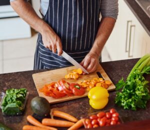 Photo shows a man cutting vegetables in a kitchen. Eating a “healthful” plant-based diet is associated with a reduced risk of Alzheimer's and other dementias, while an “unhealthful” plant-based diet is associated with increased risk