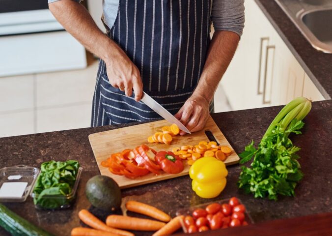 Photo shows a man cutting vegetables in a kitchen. Eating a “healthful” plant-based diet is associated with a reduced risk of Alzheimer's and other dementias, while an “unhealthful” plant-based diet is associated with increased risk