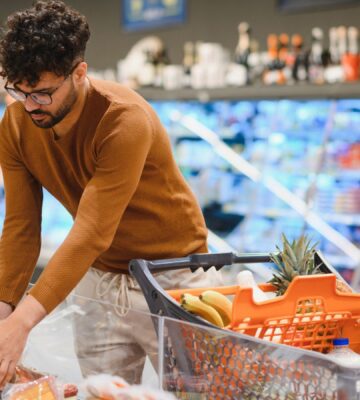 Photo shows a young man shopping in a supermarket and reaching for a pack of red meat. Plant-based mince and meatballs are currently an average of 33 percent cheaper than equivalent meat options