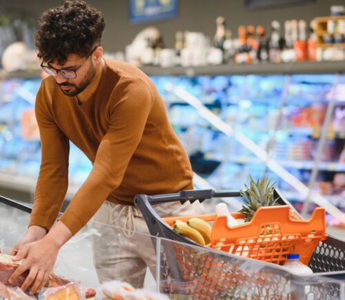 Photo shows a young man shopping in a supermarket and reaching for a pack of red meat. Plant-based mince and meatballs are currently an average of 33 percent cheaper than equivalent meat options