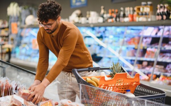 Photo shows a young man shopping in a supermarket and reaching for a pack of red meat. Plant-based mince and meatballs are currently an average of 33 percent cheaper than equivalent meat options