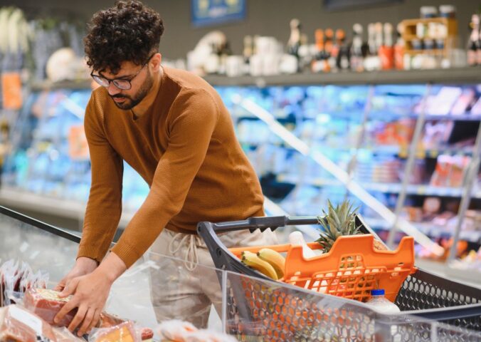 Photo shows a young man shopping in a supermarket and reaching for a pack of red meat. Plant-based mince and meatballs are currently an average of 33 percent cheaper than equivalent meat options
