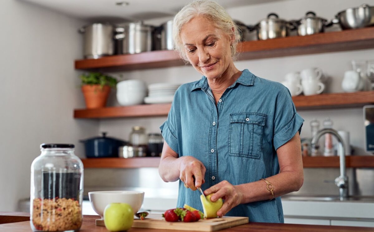 Photo shows an older woman cutting up an apple in her kitchen. A team of scientists has managed to reverse biological age in older adults using a four-week plant-forward diet