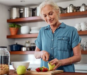 Photo shows an older woman cutting up an apple in her kitchen. A team of scientists has managed to reverse biological age in older adults using a four-week plant-forward diet