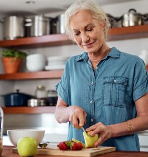 Photo shows an older woman cutting up an apple in her kitchen. A team of scientists has managed to reverse biological age in older adults using a four-week plant-forward diet