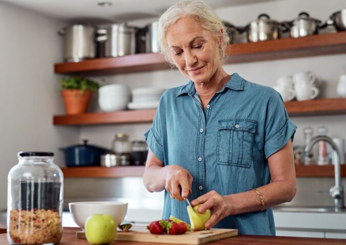 Photo shows an older woman cutting up an apple in her kitchen. A team of scientists has managed to reverse biological age in older adults using a four-week plant-forward diet